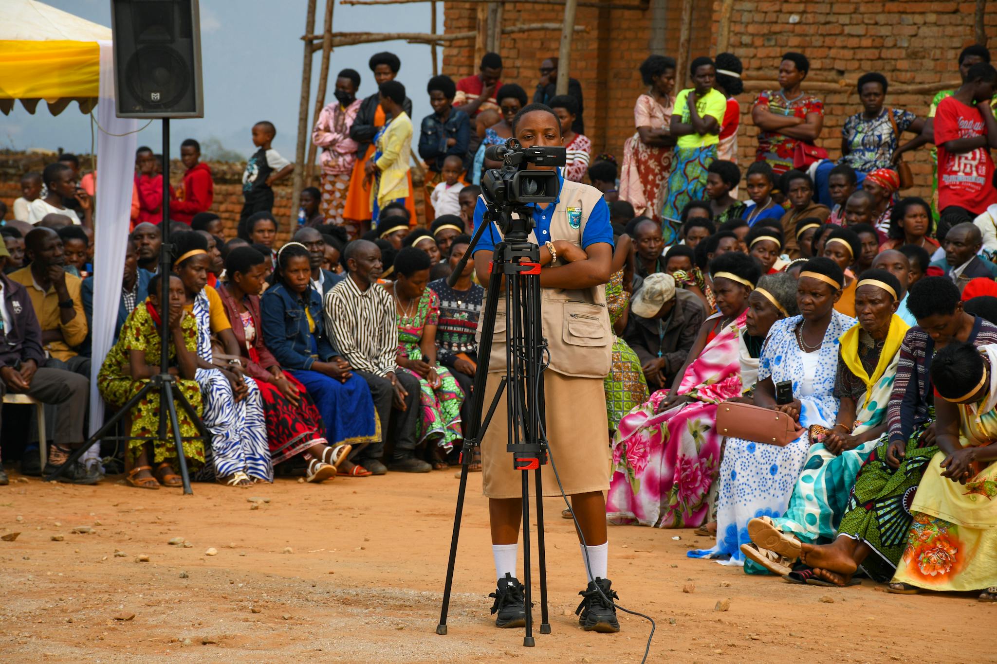 A lively outdoor event capturing a videographer amidst an attentive diverse crowd.