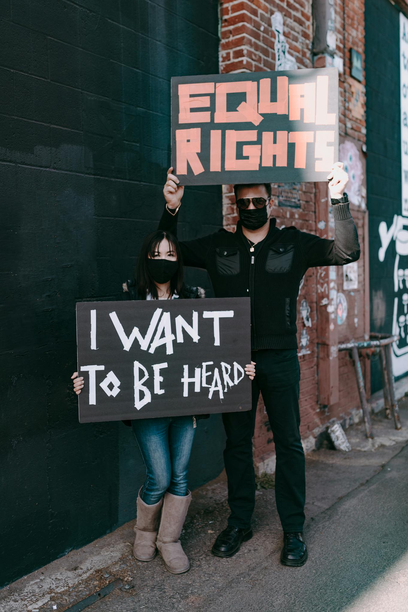 Two protesters with placards advocating equal rights and being heard, standing together outside.